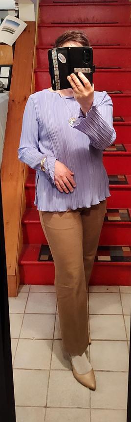 Lavender ruffly shirt with ruffly hem untucked. Straight leg camel trousers. Gold jewelry. Beige pumps.