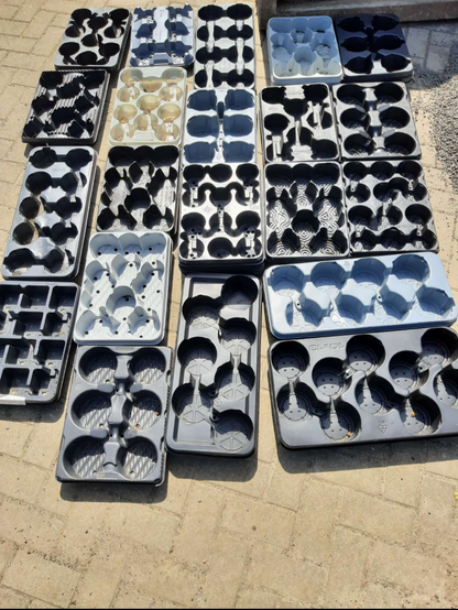 Viele unterschiedliche Wasserpaletten nebeneinander aufgereiht. Aus den Mülltonnen gefischt, aber leider nicht kompackt zu stapeln. Müll der durch die Wechselbepflanzung anfällt. (Der Friehof selbst hat nur einen Lieferanten mit einheitlichen Paletten. Das kann man dann gestapelt auch wieder dort abgeben.)