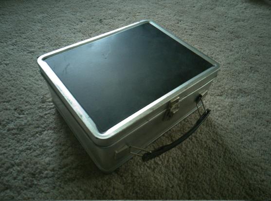 A silver lunchbox, matte black on one side.