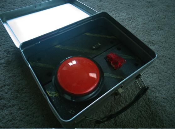 Inside the lunchbox is a black panel with yellow warning stripes. The panel has a safety toggle, a usb micro port, and a big... red... button.