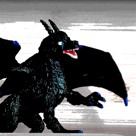 8-bit drawing with a reduced pallet (Teletext pallet). On the drawing there is a western black-scaled dragon looking right, with a left paw lifted in the air. The claws, wingclaws and the eyes are blue. The maw is opened, with white teeth and red flesh.