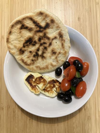 Fresh pita, fried halloumi, and a tomato, cucumber, and olive salad.