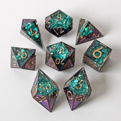 Ein Würfelset in lila/grünem Colorshift mit einer Geode-Seite in Grün. Das Set besteht aus einem D4-Shad, einer D4-Pyramid, D6, D8, D10, D100, D12 und D20. Das Set liegt auf weißem Untergrund. Die Würfel sind im Bild um den D20 angeordnet. Die Würfel liegen mit der Geode Seite nach oben.