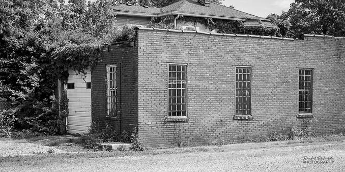 A one story garage structure with a flat roof.  There is one garage door and window on the end and three windows on the side.