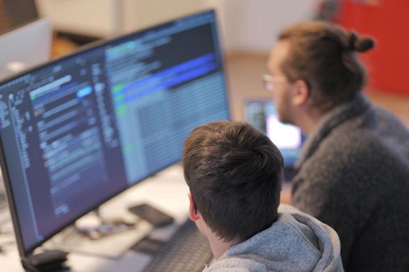 Unsere DevOps Engineers Markus und David besprechen etwas vor einem Computerbildschirm mit offenen Terminals.