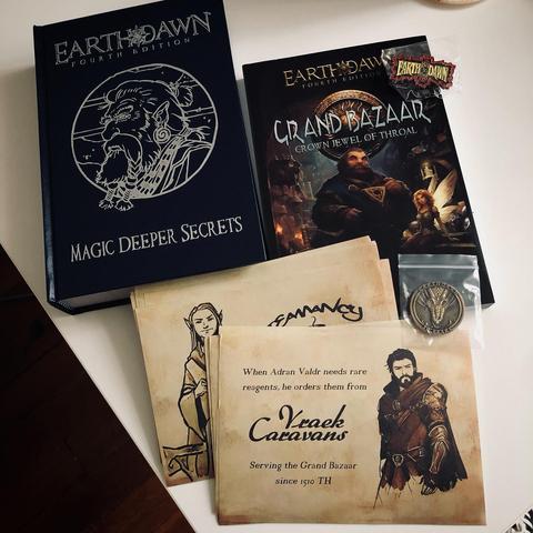 Photo d'un coin de table où sont posés plusieurs ouvrages de la quatrième édition du jeu de rôle Earthdawn, notamment "Grand Bazaar" et l'édition deluxe de "Magic Deeper Secrets".