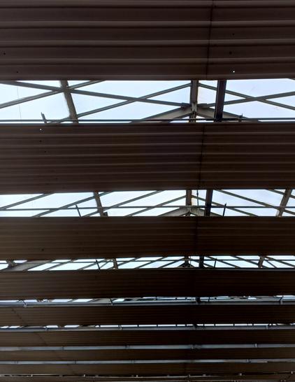 A photo of zinc paneling beneath a rooftop skylight at a mall, and the triangular shapes formed by the skylight's support beams.