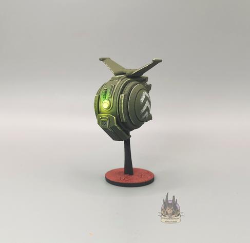 Drone - it's spherical with stablising fins at the top, in a drab green with grey chevron patterns on the side panels - front right view