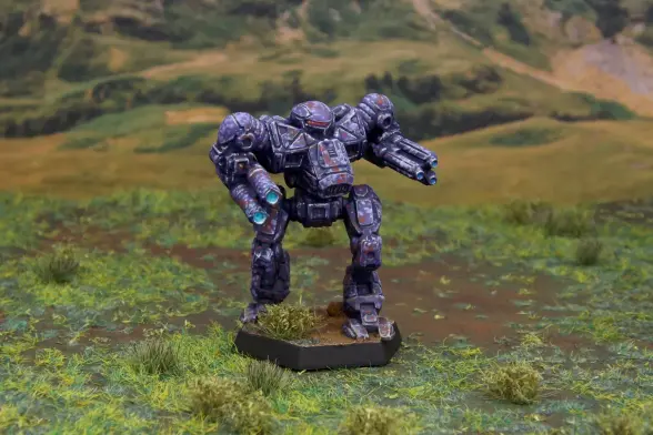 A painted miniature of a Nova Cat 'Mech. It is painted in a predominantly purple camo pattern with dots of lighter purple and rust red. The cockpit glass is pink. The miniature is photographed on grassy terrain.