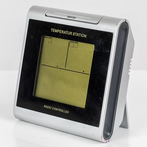 Vorderansicht. Mittig das gelbliche LCD-Display, am oberen Rand eine "Snooze"-Taste