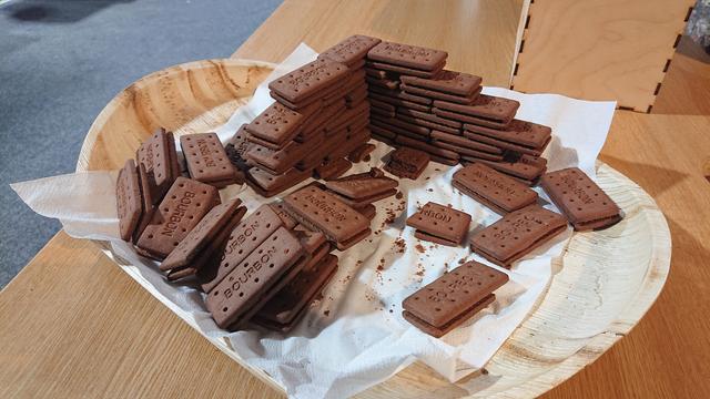 A plate containing many bourbon cream biscuits.  Given they are broadly brick-shaped, about half of them have been assembled into a wall with a 90 degree corner, six courses high.  Stretcher bond, I think