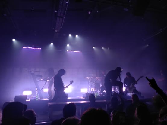 Australian metalcore band "Make Them Suffer" doing their thing on a stage illuminated by purple lights