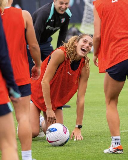 Sharples kneeling on the ground and laughing during training