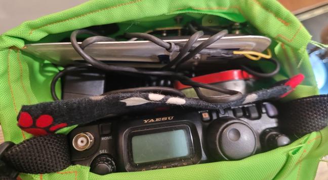 Two pocket DIY sewn padded bag with a Yaesu Ft818ND ham radio and a Morse Code key made out of an old license plate crammed into pockets. Bright green bag with a divider in dog themed fleece