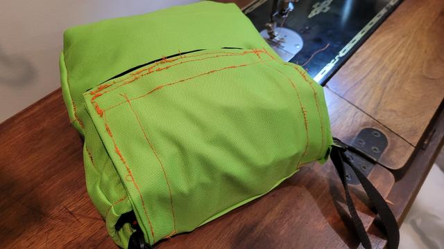 Horrible, horrible sewing job where you can see the tension on a bobbin went out of whack on sewing on the outside of a green bag. Extremely obvious because it was done with a neon orange thread