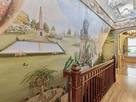 A hallway that is entirely covered in murals of a large field with a monument and a Greek bust.