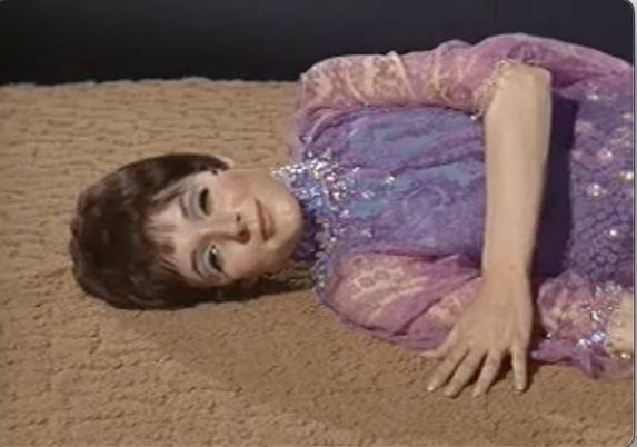The empath from Star Trek the Original Series lays luxuriously on a beige rug facing the camera.