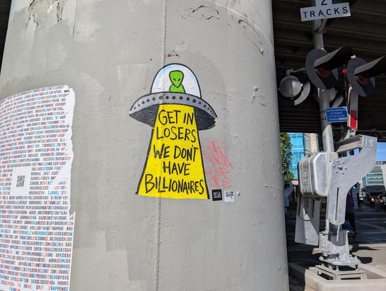A street art piece. It's an alien blasting a beam of light that says "Get in losers we don't have Billionaires"