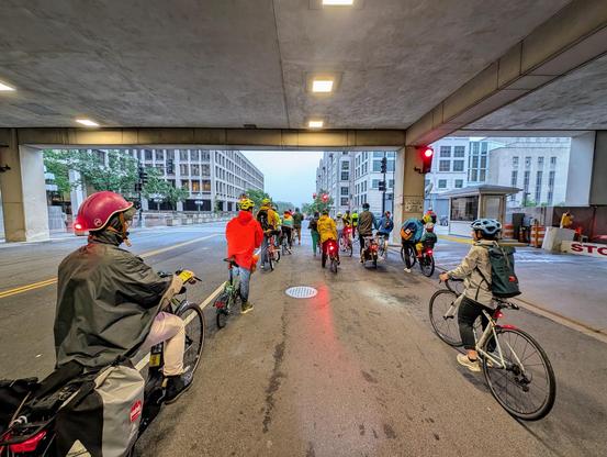 A shot from the back of a group of cyclists in an underpass, stopped at a red light.