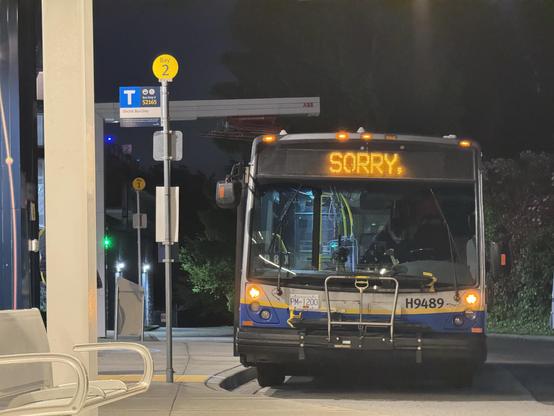A 2009 TransLink Nova Bus LFS parked at Bay 2 at 22nd Street Station. Its destination sign says “Sorry”. The stop pole sign distinctly says “Electric Bus Only”. It’s very clearly night time and the photo was taken from another bus bay.