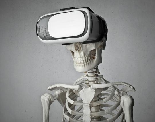 portrait photo of skeleton in front of gray background with white and black vr goggles on