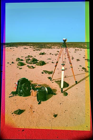 A color composite photo of a survey instrument on a tripod and some gear on the ground with a lot of basalt in the distance.