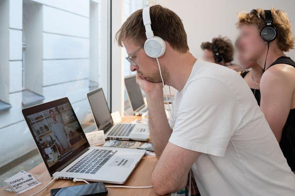 Exhibition detail: people watching a video on laptops