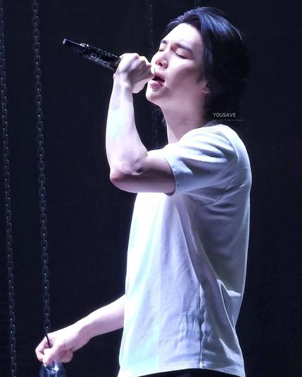 Suga of BTS in a white t-shirt, singing into a microphone.