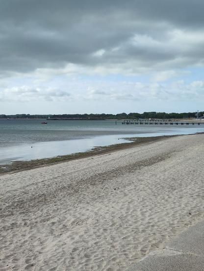 Strand, graue See, Regenwolken.