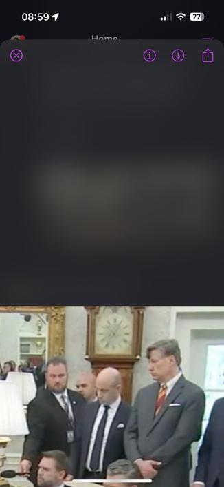 The image is made in the Oval office with tRump. Several men are standing, and one man appears to be seated, possibly speaking into a microphone. The room features decorative elements including a large clock and lamps.