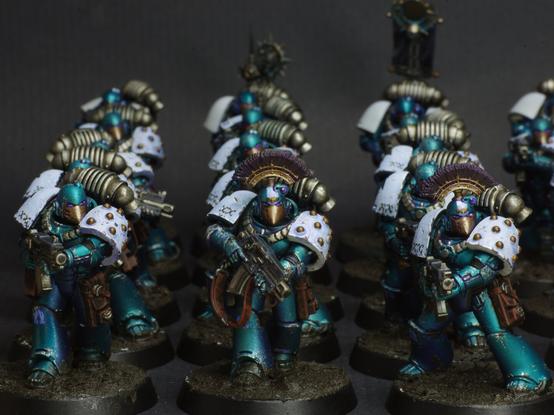 Photo of a squad of a squad of tactical astartes of the Alpha Legion from the Horus Heresy. They're wearing mkVI armour, painted in mettalic blue with white shoulder pads.