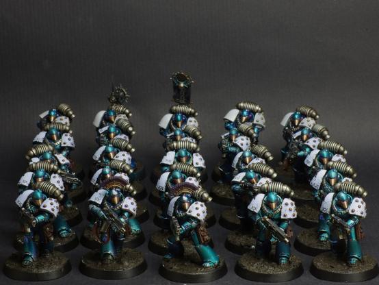 Photo of a squad of a squad of tactical astartes of the Alpha Legion from the Horus Heresy. They're wearing mkVI armour, painted in mettalic blue with white shoulder pads.