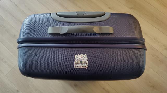 Luggage with a Solder Party sticker on top.