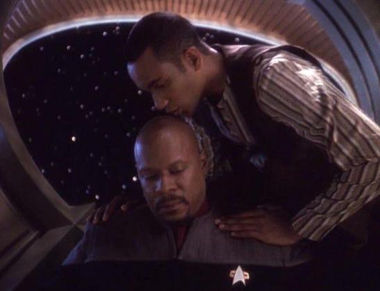 Jake Sisko kisses the top of his father's head, Benjamin Sisko, in a still from the television show STAR TREK: DEEP SPACE NINE.