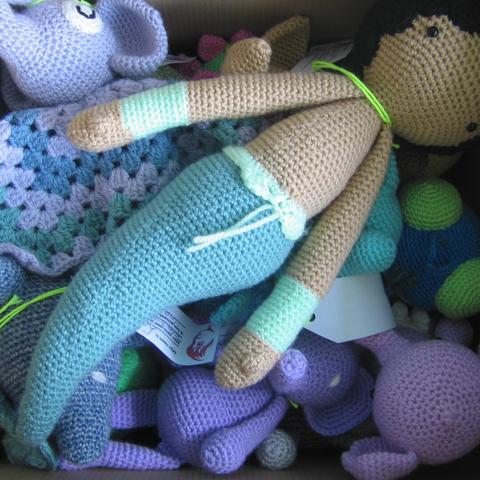 A picture of the inside of a box filled with all sorts of amigurumis, a mermaid being on top.
