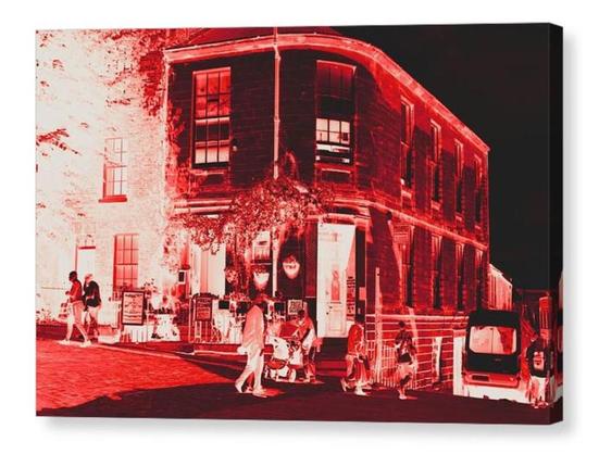 Colour adjusted - it's very red on a black background - photograph showing a cafe on a street corner that's advertising scones.  The image is shown printed upon a block canvas.