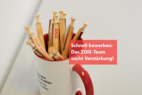 Foto einer Kaffeetasse gefüllt mit Holzkugelschreibern mit ZOiS-Logo, im Vordergrund der Text "Schnell bewerben: Das ZOiS-Team sucht Verstärkung!"