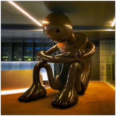 A semi-abstract bronze sculpture of a sitting/crouching kid.