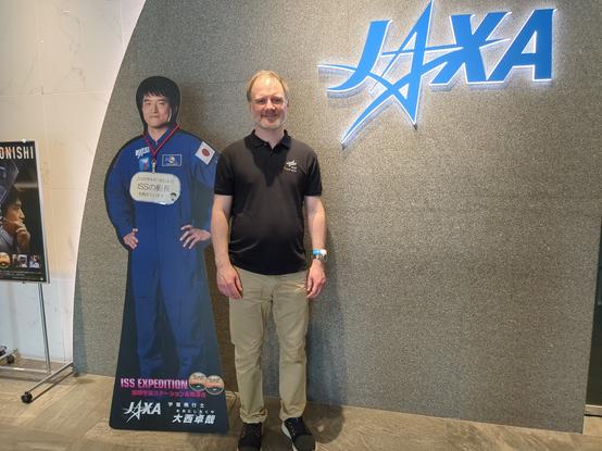 Me standing in between a cardboard astronaut and a JAXA at the Tsukuba Space Center