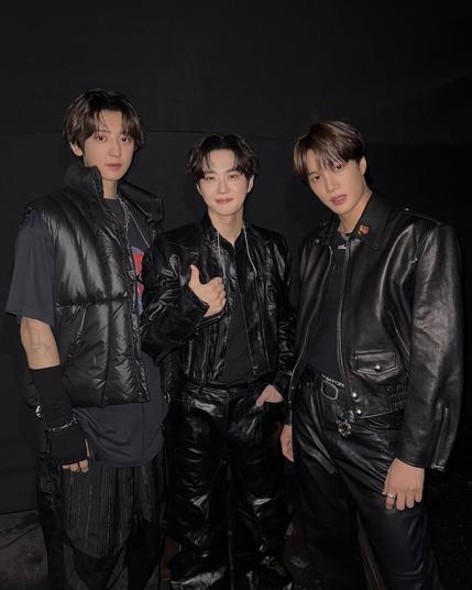 Chanyeol, Suho and Kai all wear black leather outfits for their "Git It Up" performance. Suho smiles and gives a thumbs up.