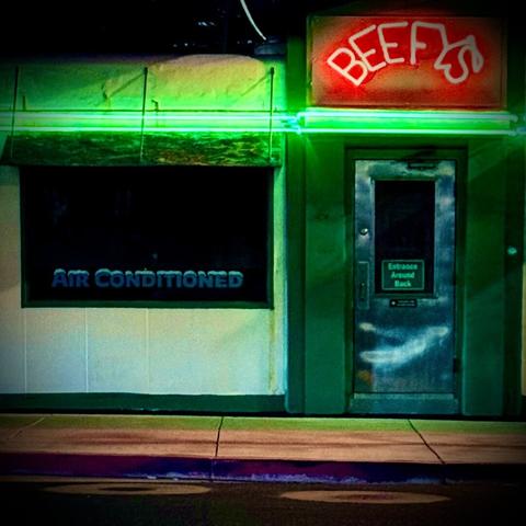 Little burger joint called BEEFY'S. The photo is taken and night and it has green neon lights illuminating the building and a sign in red neon. 

An added bonus is that the place is air conditioned, as noted by the lettering on the window, written in a font that looks like it's covered in snow/ice so you get the full effect.