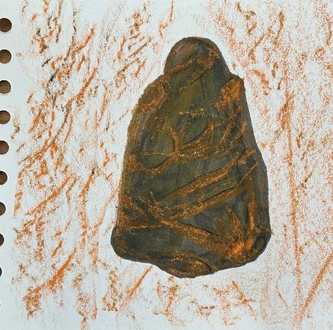Mixed media sketch of a pebble, ochres, browns and grey with lines. Shape is reminding me of a figure. The surrounding background is made up of rubbings of the pebble, creating textured lines.