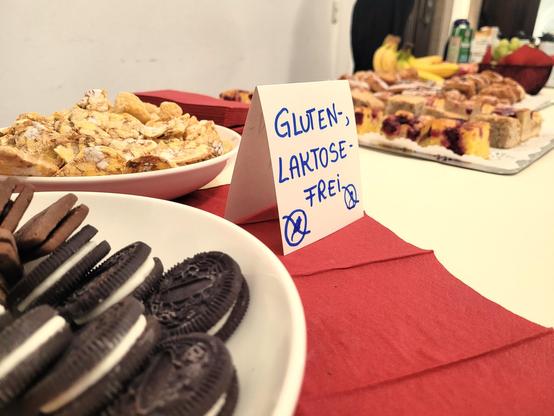 Viele Snacks gab es auch: Es sind mehgere Teller mit Keksen und  süßen Teilchen zu sehen und daneben ein Schild: Gluten und Laktosefrei