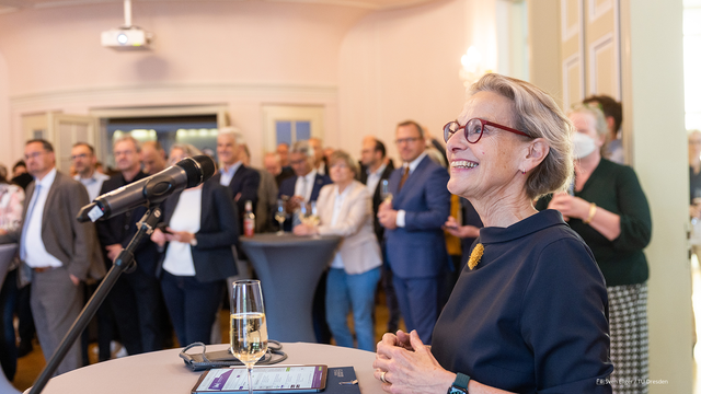 Foto von Rektorin Prof.in Ursula Staudinger bei der Verkündung zu den Exzellenzclustern. Im Hintergrund sind weitere Menschen unscharf abgebildet.