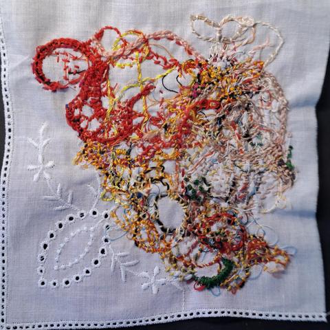 Ein paar Fadenreste aus der textilen "Mülltüte" wurden auf einem Viertel eines Taschentuchs zum Umhäkeln aufgenäht.