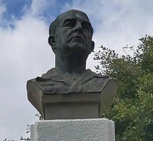 Busto de una persona mayor, con aspecto serio, sobre un pedestal, en un espacio público