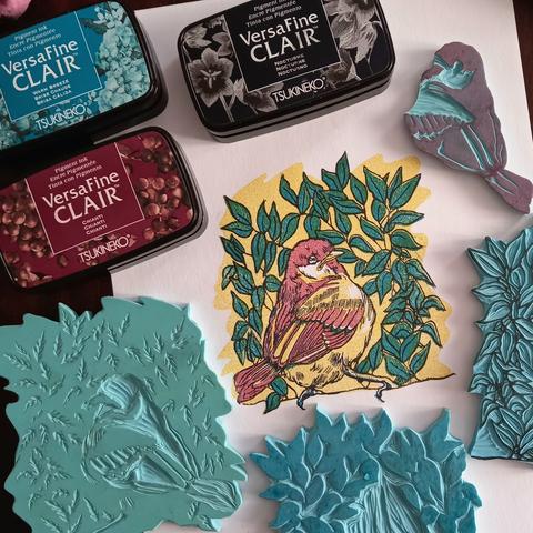 4 plaques de vinyle gravées à la main, les encres pour tampons utilisées et le résultat de l'impression de cette estampe colorée, petit oiseau tout rond et feuillage.