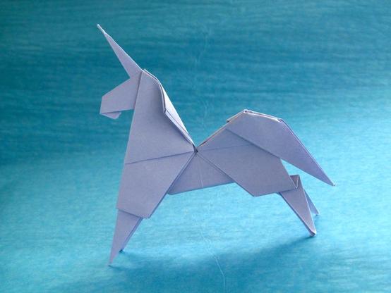 A stylised lilac unicorn folded from paper with a few cuts. The background blue background. A mane is suggested by curving the paper.