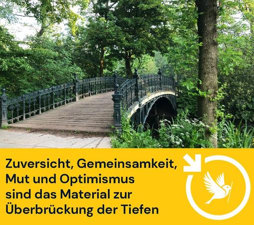 Eine Brücke mit gusseisenernem Geländer und Holzbohlen führt in einem schönen, grünen Park über einen kleinen Fluss.
Unter dem Bild steht "Zuversicht, Gemeinsamkeit, Mut und Optimismus sind das Material zur Überbrückung der Tiefen.
Unten rechts ist unser Logo: der Ulmer Spatz im Pfeilkreis von LocalZero. (Pfeilkreis bedeutet: Ein Kreis, an dessen oberer linken Seite ein Pfeil nach unten weist)