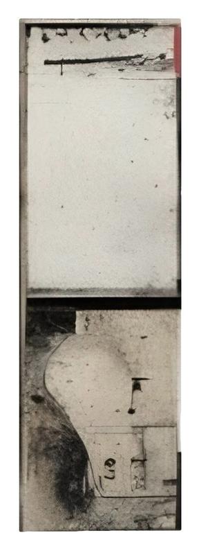 A narrow, vertical composition with a mostly empty upper section that fades into soft, weathered textures. The lower half features worn architectural fragments — a shadowed niche, abstracted curves, and faint numeric marks. The top edge is punctuated by blackened cracks and a small patch of red, like a remnant of painted surface. The image reads like a forgotten monument or a cross-section of a wall, highlighting absence as much as form.